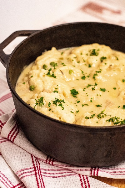 A side shot of a cast iron dutch oven full of chicken and dumplings 