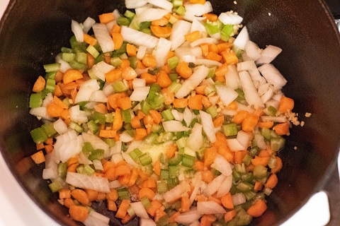 chopped onions, carrots, garlic, melted buter, and chopped celery cooking  in a dutch oven. 