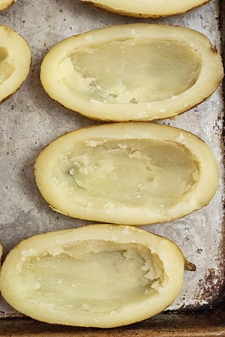 Hollowed out potato skins on a baking sheet. 