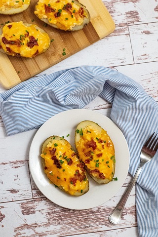 twice baked potatoes on a white plate with a fork and a blue and white striped linen. 