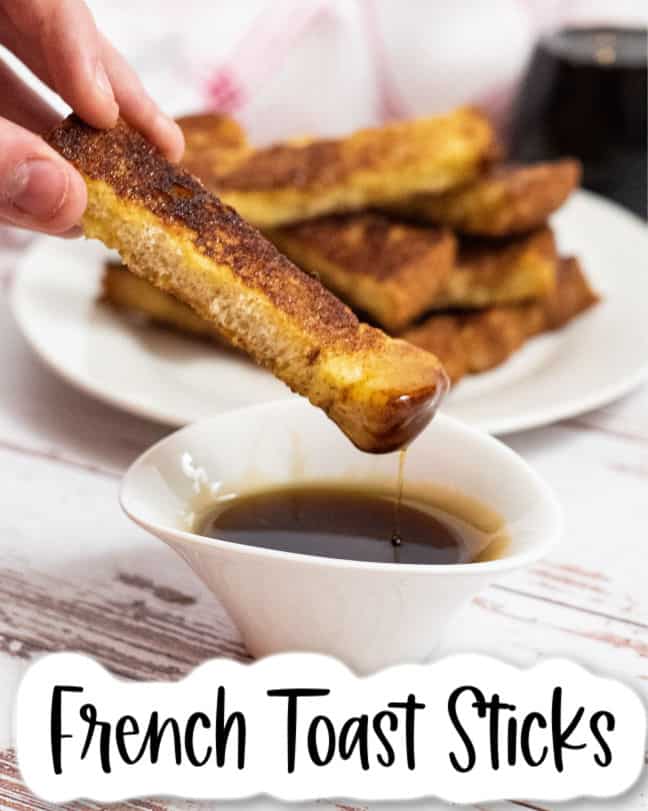 a french toast stick being dipped in maple syrup 