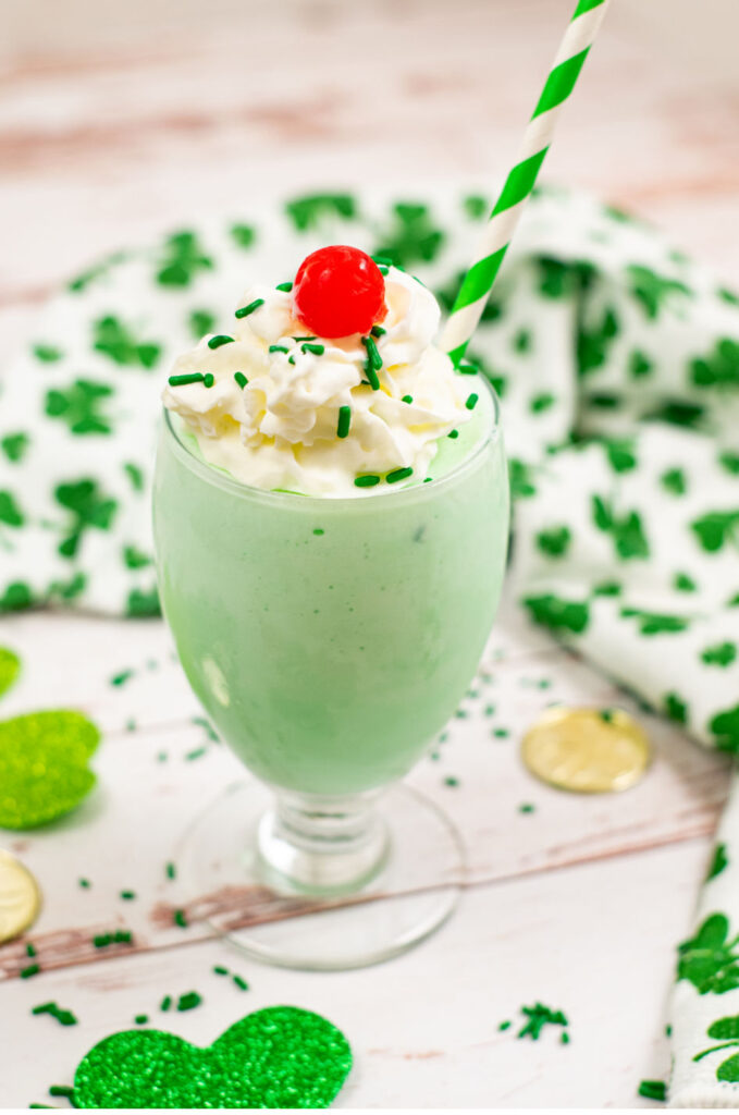 A green milkshake topped with whipped cream and a cherry