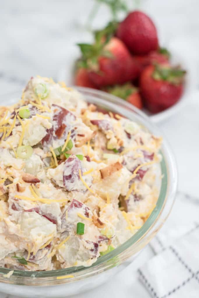 A clear glass bowl full of potato salad 