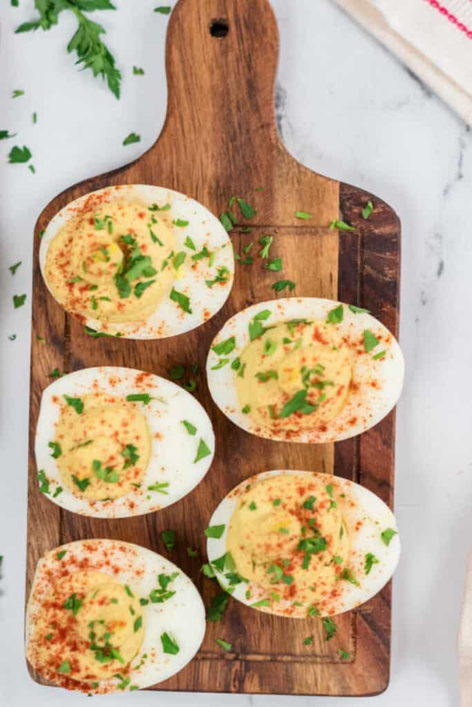 5 deviled eggs on a wooden board 