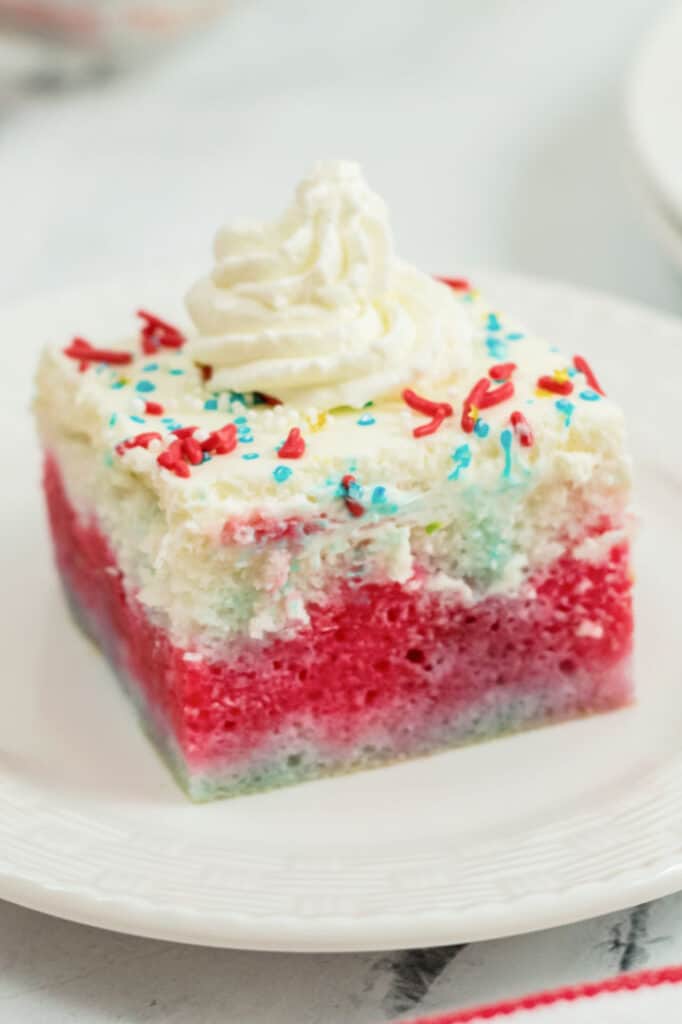 A piece of red white and blue poke cake  on a white plate. 