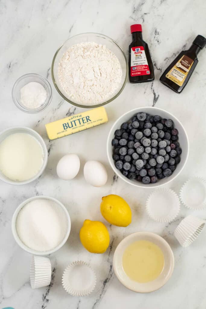 The ingredients for lemon blueberry muffins laid out on a marble countertop 