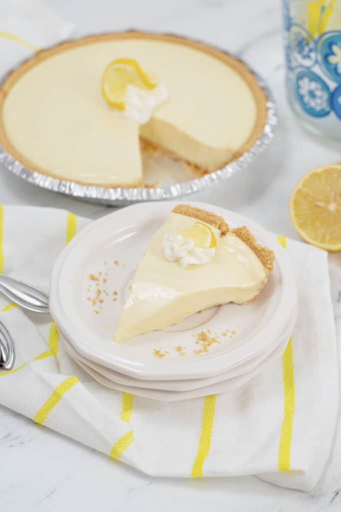 A piece of lemon pie on a stack of small white plates 