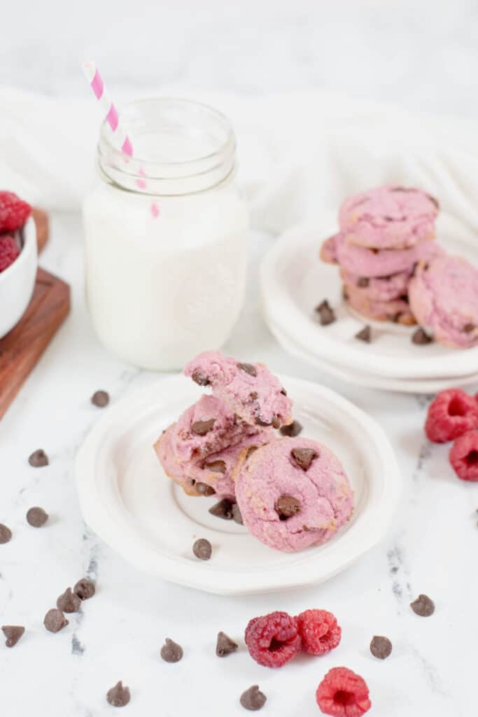 Plates of raspberry cookies and a mason jar full of milk 