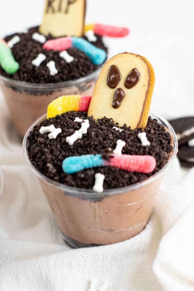 A pudding dirt cup with a Milano cookie with a ghost face on it. 