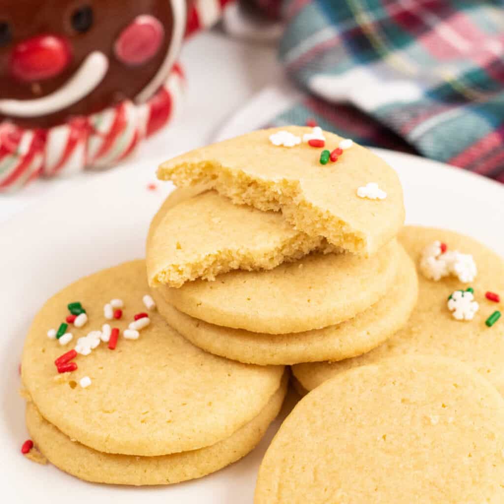 A pile of sugar cookies on a white plate. 