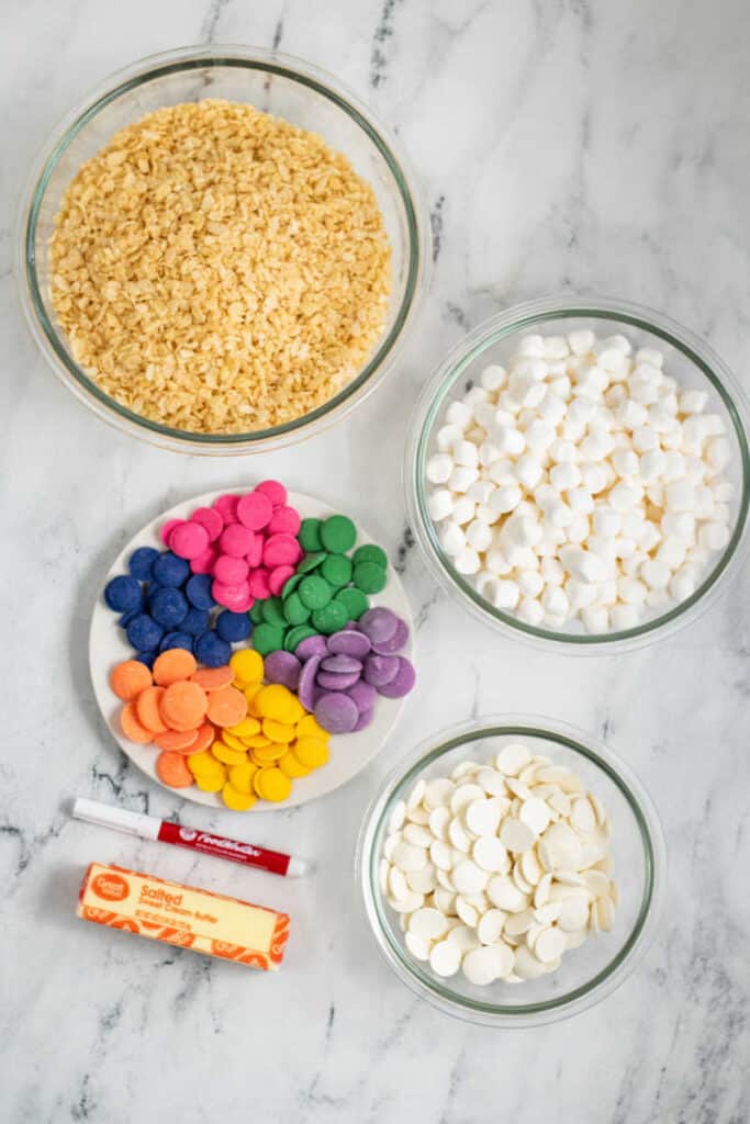 The ingredients for making conversation heart rice krispie treats. Crispy rice cereal, marshmallows, butter, and colored candy melts 