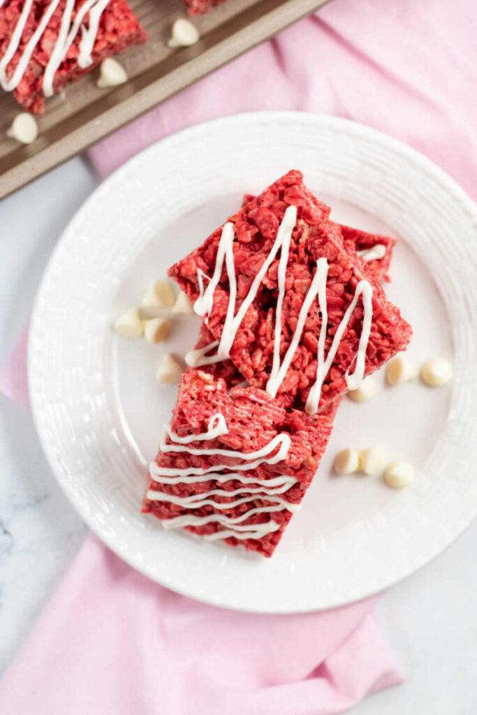 A stack of red velvet cereal treats on a white plate. 