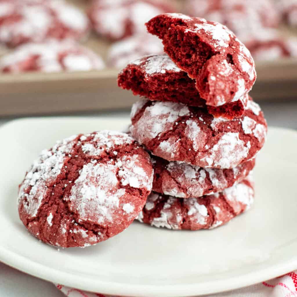 A stack of red velvet crinkle cookies on a white plate 