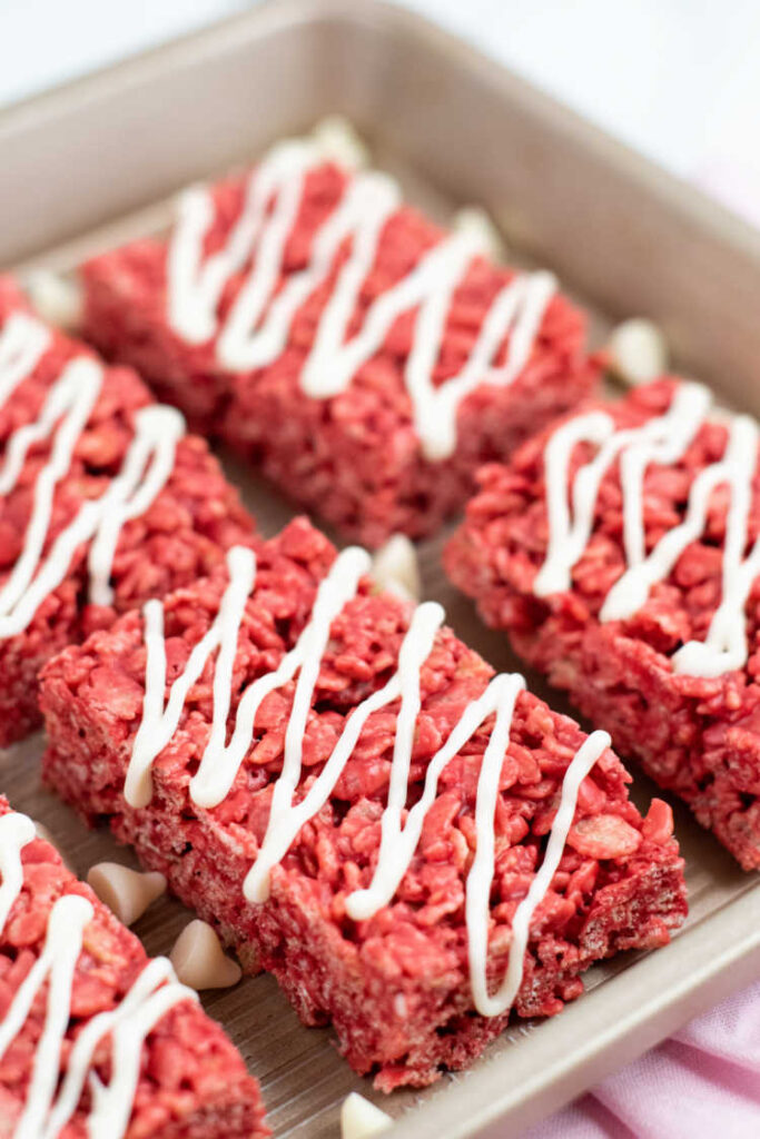 Red velvet rice krispie treats on a metal baking sheet. 