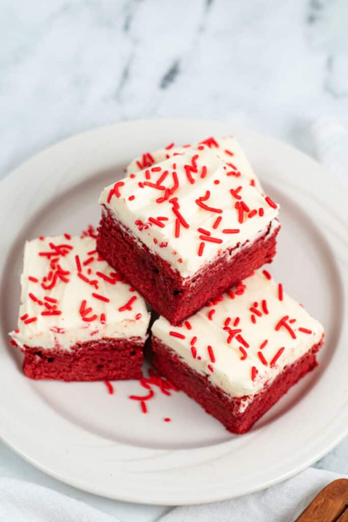 A stack of red velvet brownies on a white plate. 