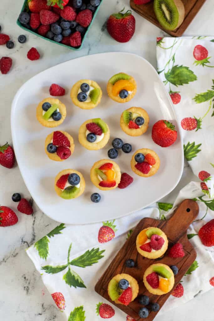 A white plate covered with mini fruit tarts. 