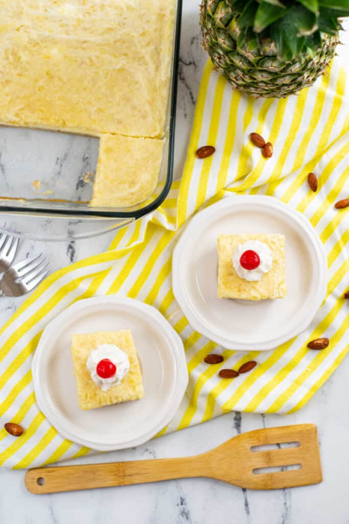 Two pieces of pineapple cheesecake squares on white plates 