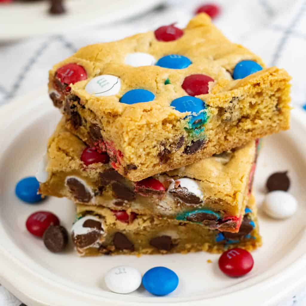 A stack of red white and blue cookie bars on a white plate 