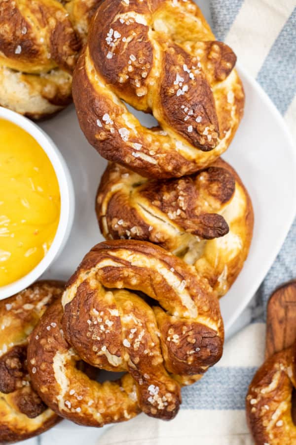 A stack of soft  pretzels on a white plate. 