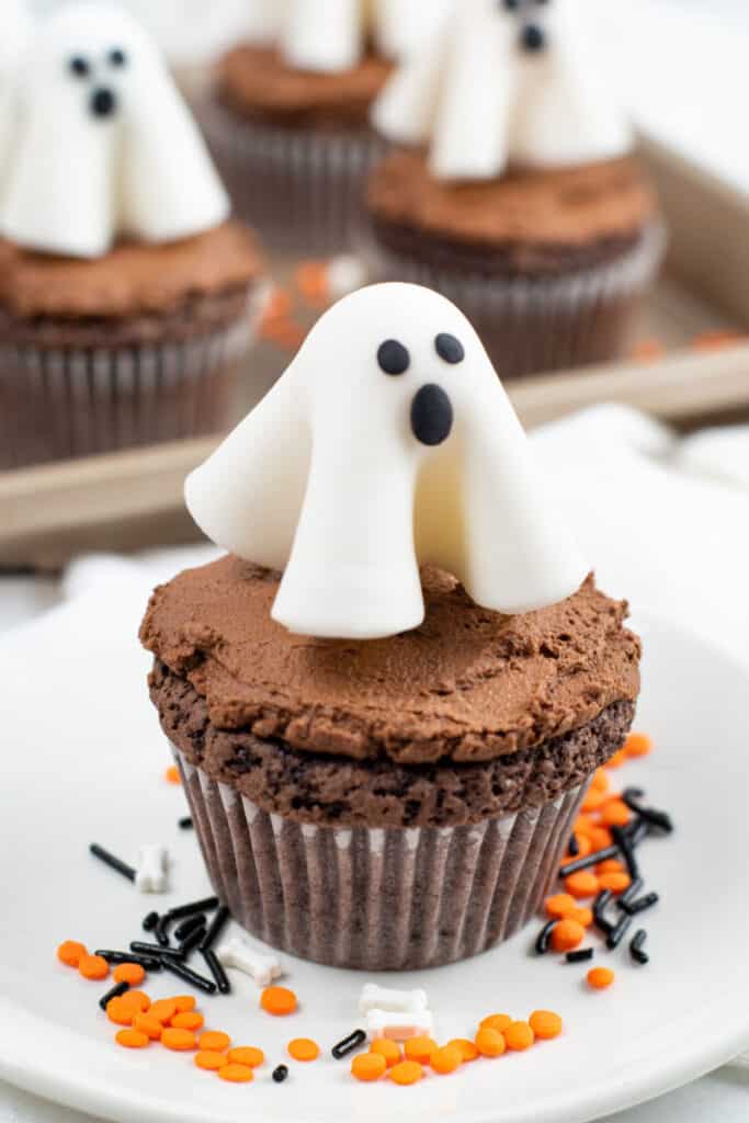 a chocolate frosted cupcake topped with a ghost made of fondant. 