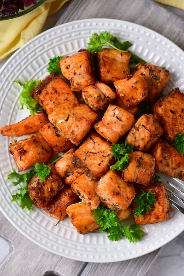 a plate of cooked salmon bites garnished with parsley. 