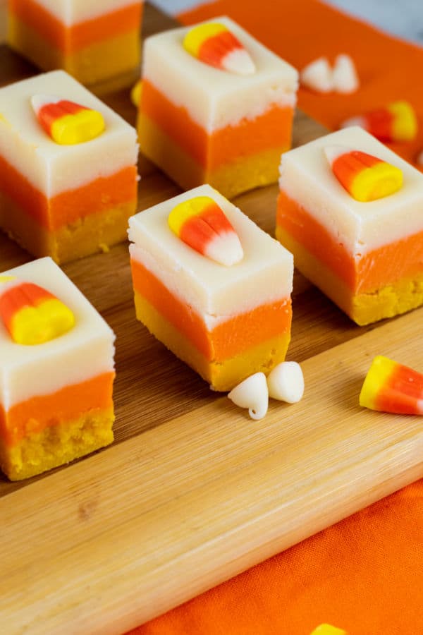 Squares of candy corn fudge on a wooden chopping block 