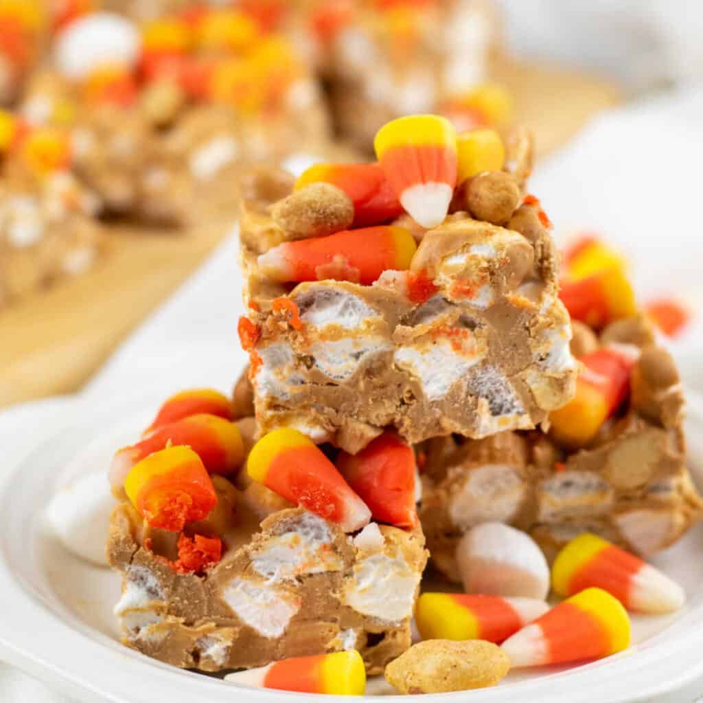 A stack of marshmallow peanut butter candy corn bars on a white plate. 