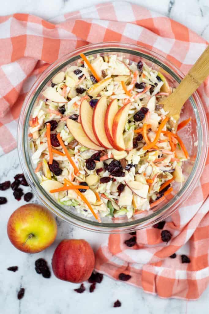 A clear glass bowl full of cranberry apple coleslaw.