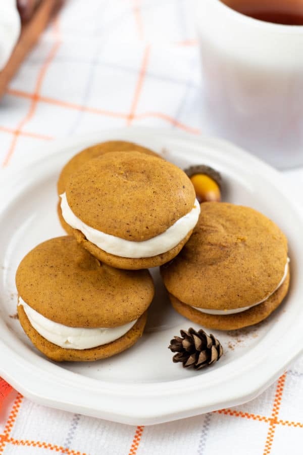 A pile of pumpkin whoopie pies on a white plate. 