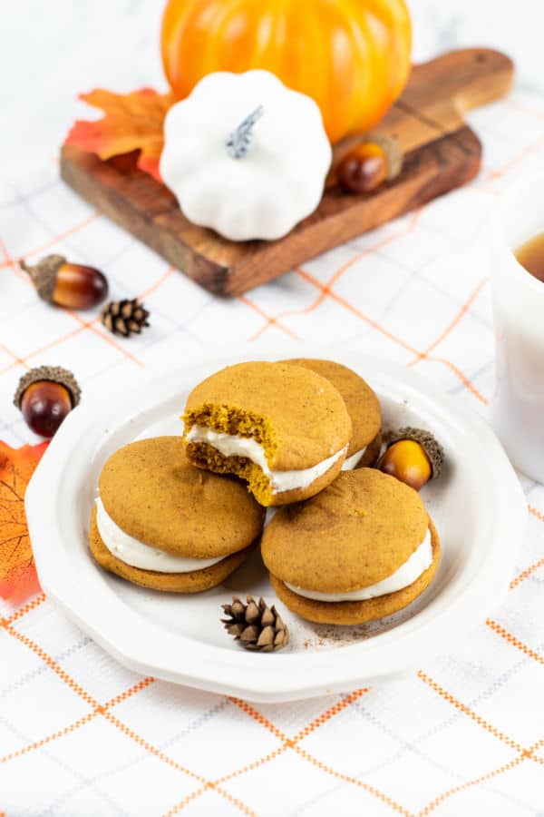 A stack of pumpkin whoopie pies on a white plate. 