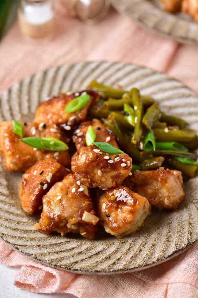 a close up of a plate of easy sesame chicken with green beans. 