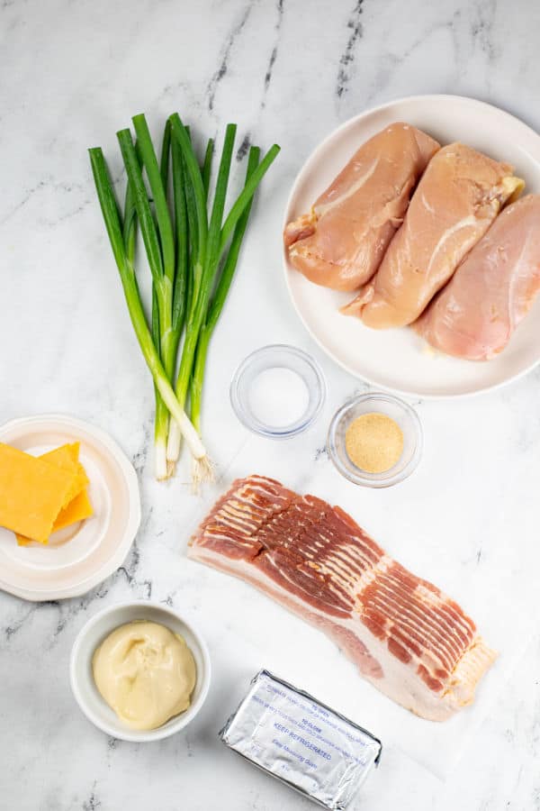 The ingredients for million dollar chicken. Boneless skinless chicken breasts, green onions, salt, garlic powder, cheddar cheese, bacon, mayonnaise, and cream cheese. 