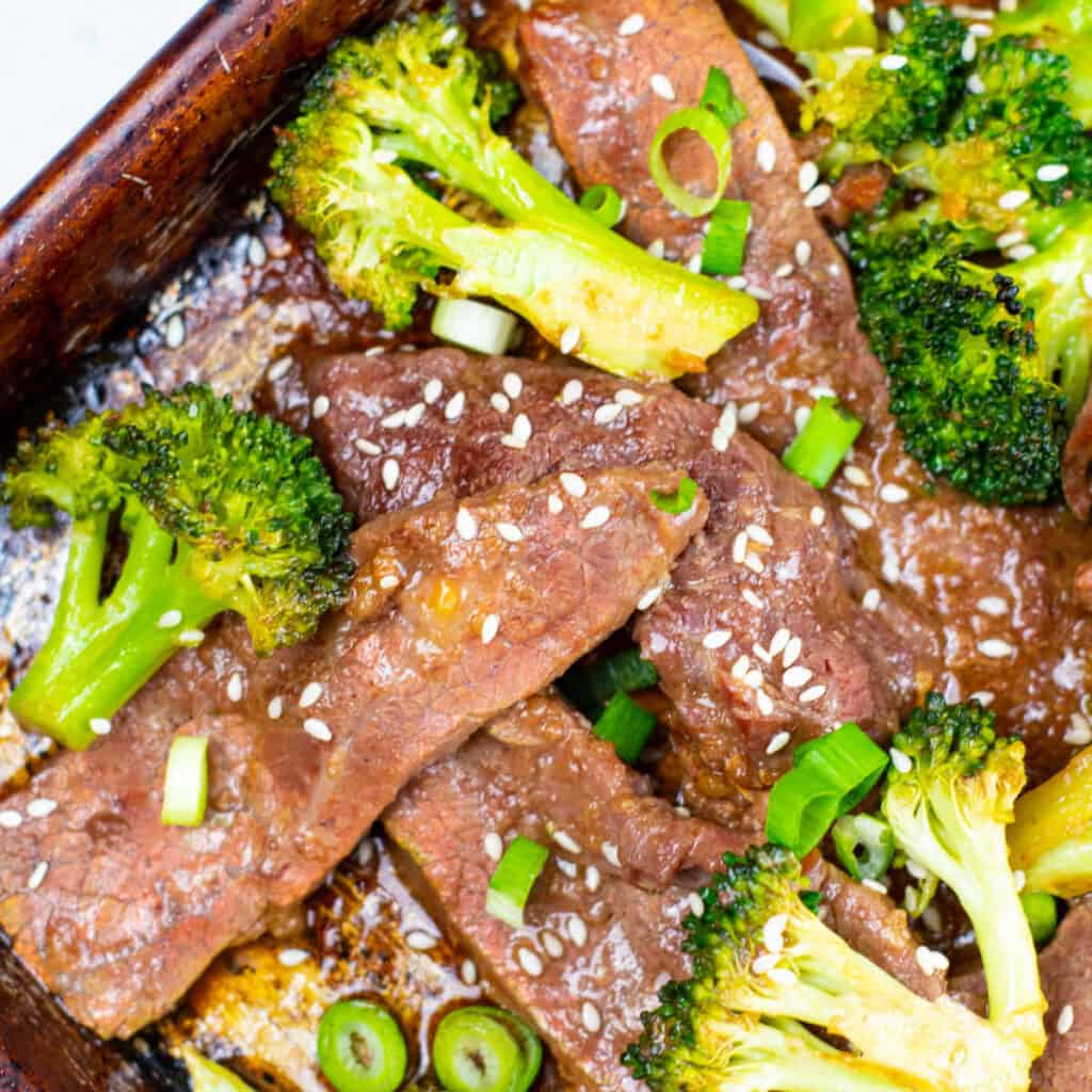 A close up of sheet pan beef and broccoli sprinkled with sesame seeds. 