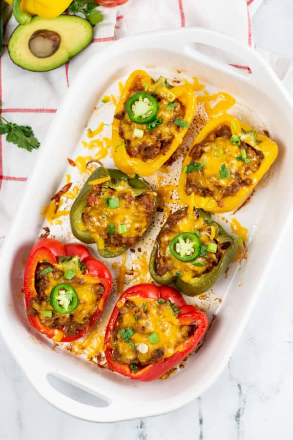 A white baking pan with 6 stuffed peppers cooked in it. 