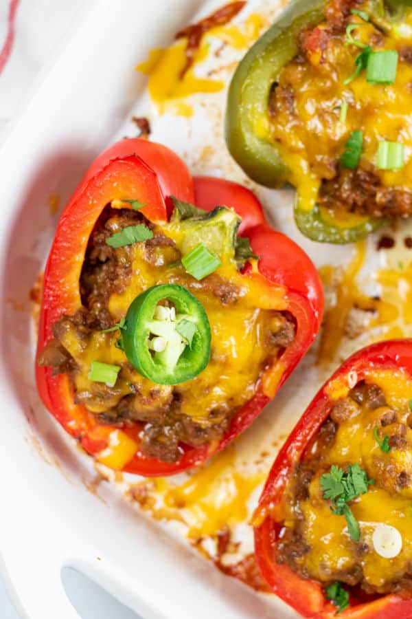 A close up of a red pepper stuffed with a meat mixture and topped with cheese and jalapeno