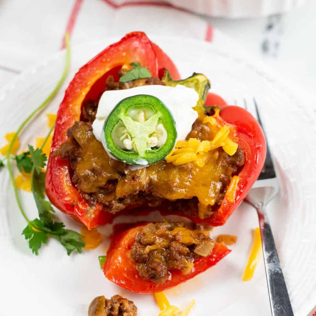 A red pepper stuffed with a meat mixture and topped with cheddar cheese sour cream and sliced jalapeno.