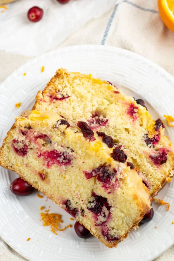 two pieces of cranberry orange pound cake on a white plate. 