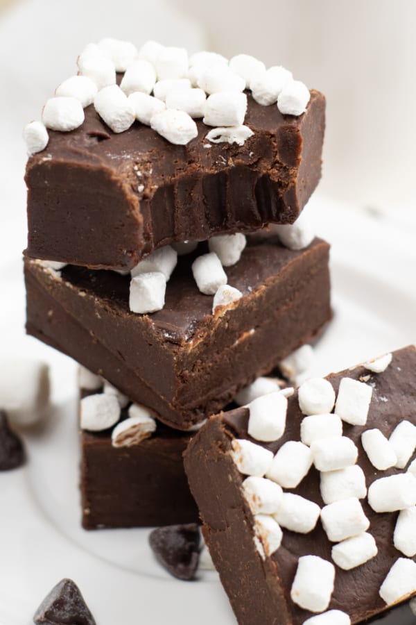 A pile of hot chocolate fudge. A bite is taken out of the top piece showing the rich creamy texture of the fudge. 