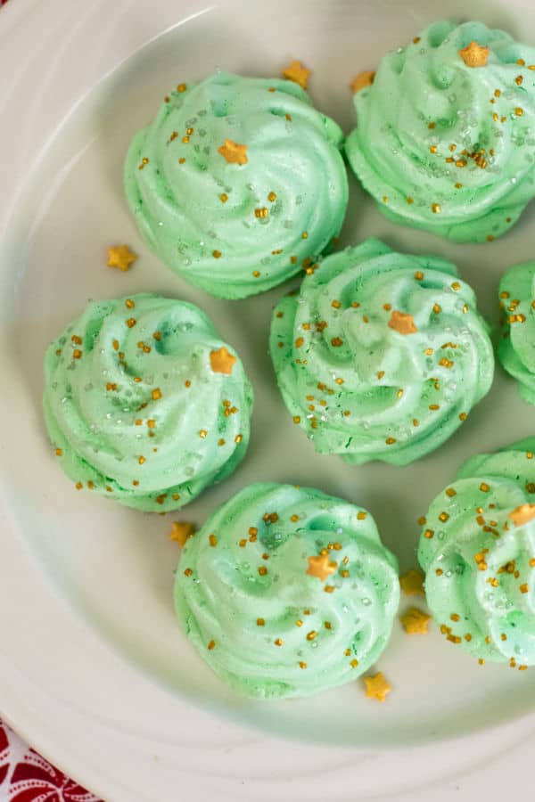 A plate full of green Christmas tree meringues.