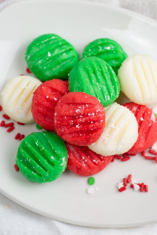 a pile of green red and white cream cheese mints on a white plate. 