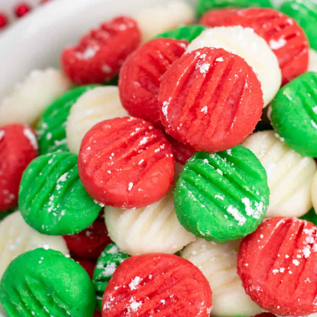 A close up of a pile of red green and white cream cheese mints. 