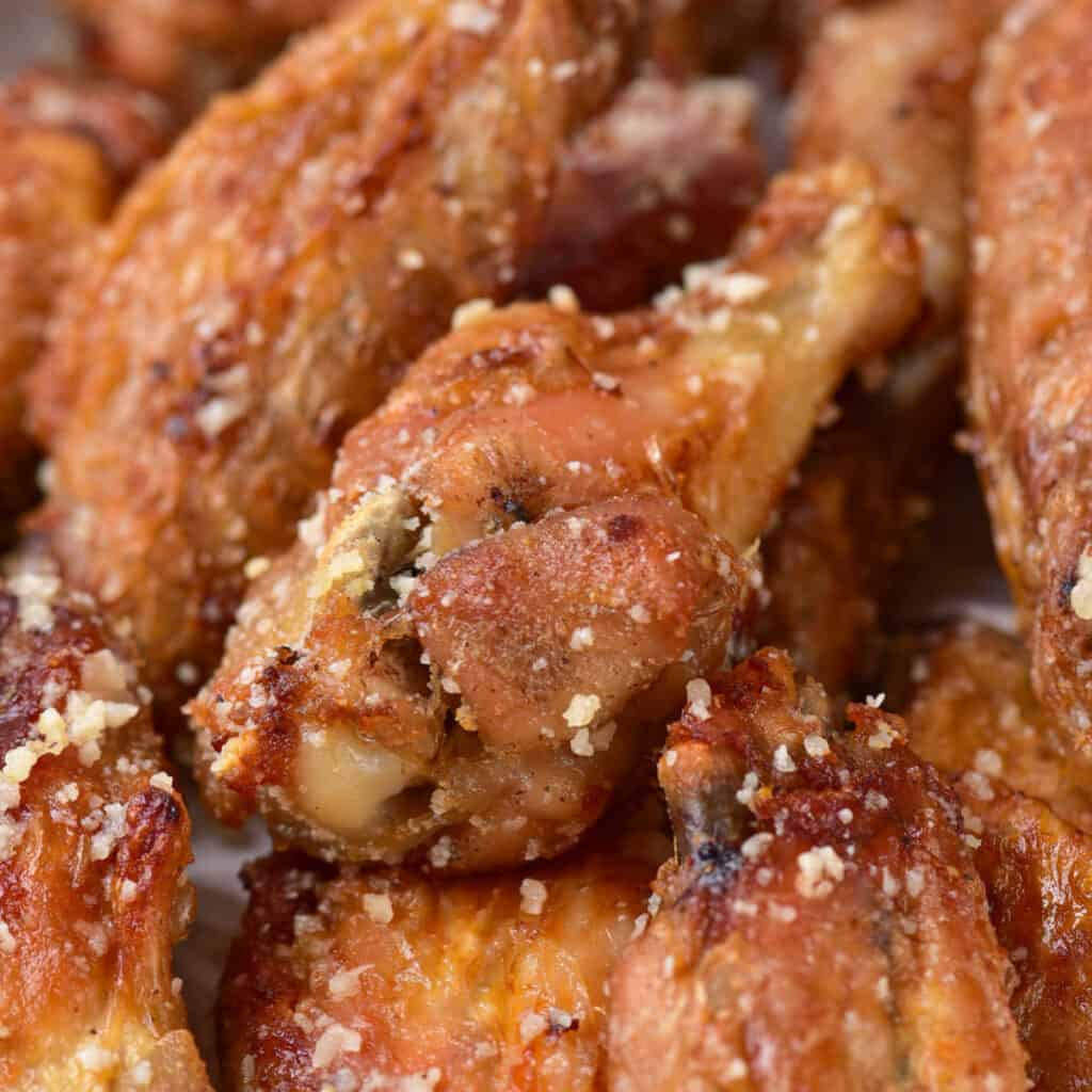 A close up of a pile of golden brown garlic parmesan wings. 