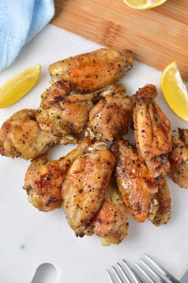 A pile of lemon pepper chicken wings  on white parchment paper. 