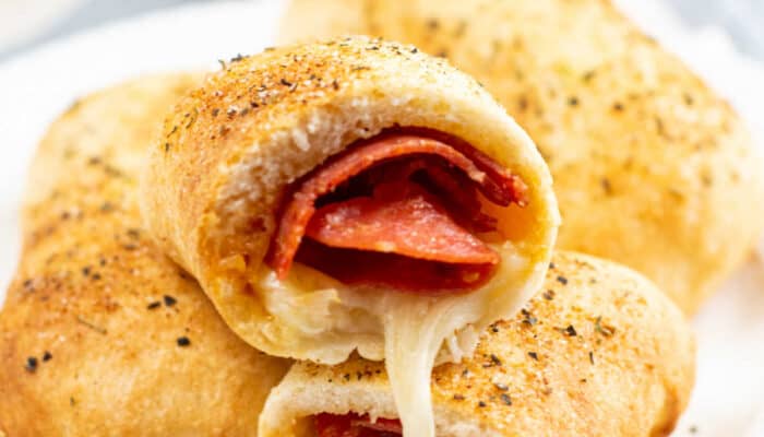 A small white plate of air fryer pepperoni rolls sitting on a dish towel.