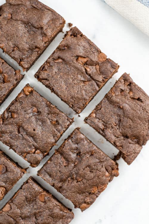An overhead view of several brownies arranged in a grid on a marble countertop.