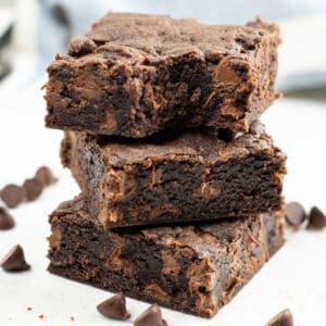 A stack of three cake mix brownies on top of a marble countertop, one with a bite out of it.