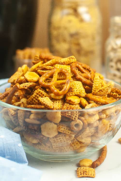 A large glass bowl of air fryer chex mix on a marble countertop.