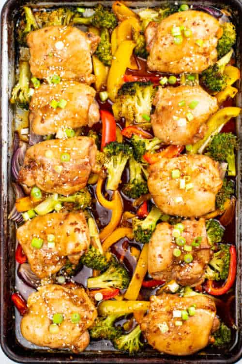 An overhead view of a sheet pan of teriyaki chicken and various mixed vegetables.