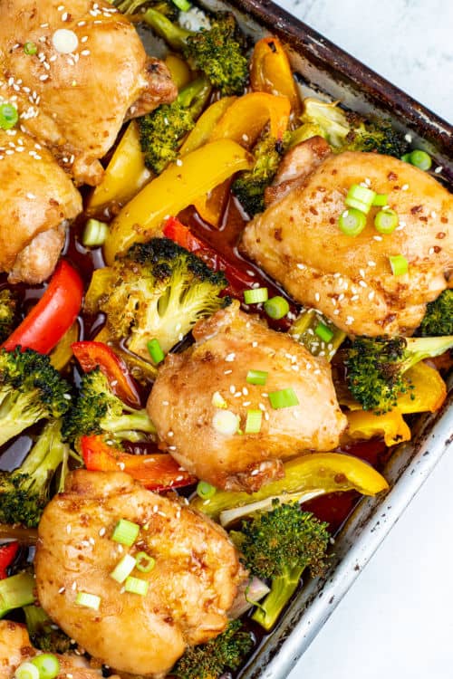 An overhead view of a sheet pan of teriyaki chicken and various mixed vegetables.