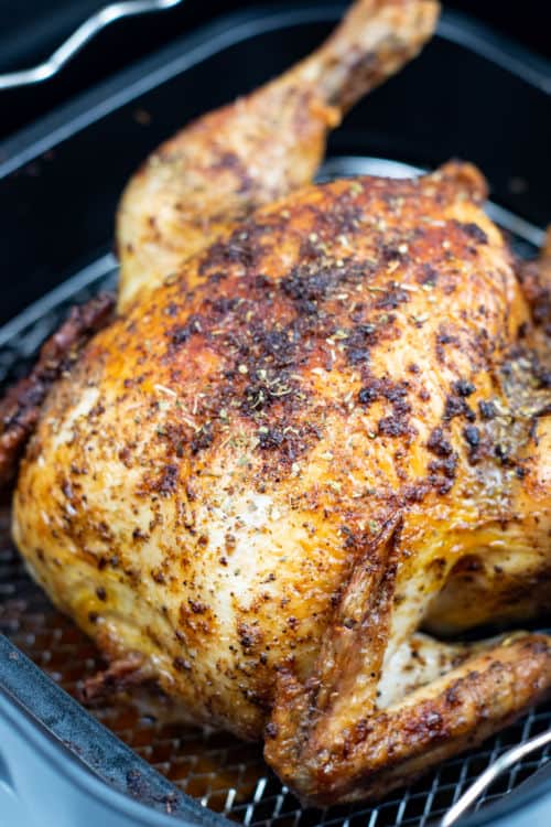 A close up of a roasted chicken in an air fryer.